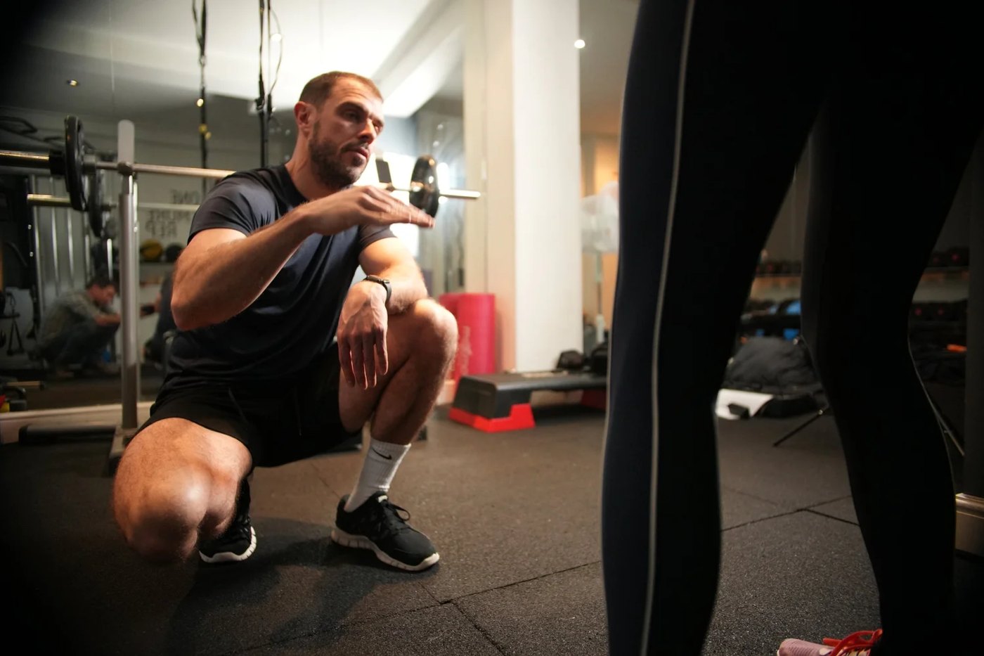 Matthew coaching a client through a squat in the gym